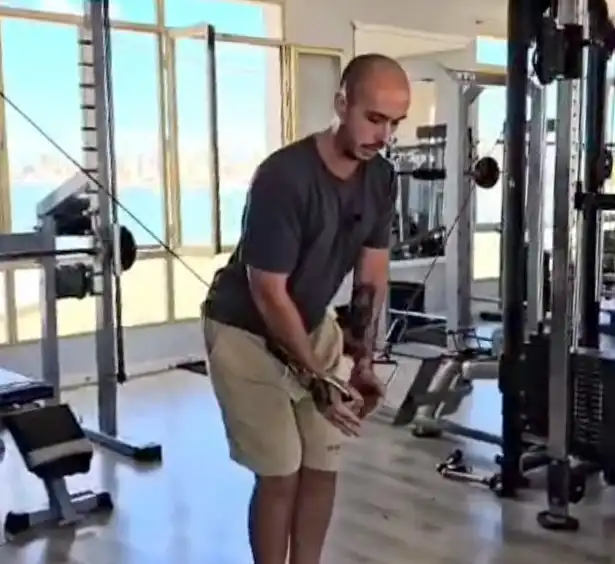 Persona realizando cruce de poleas en máquina de gimnasio