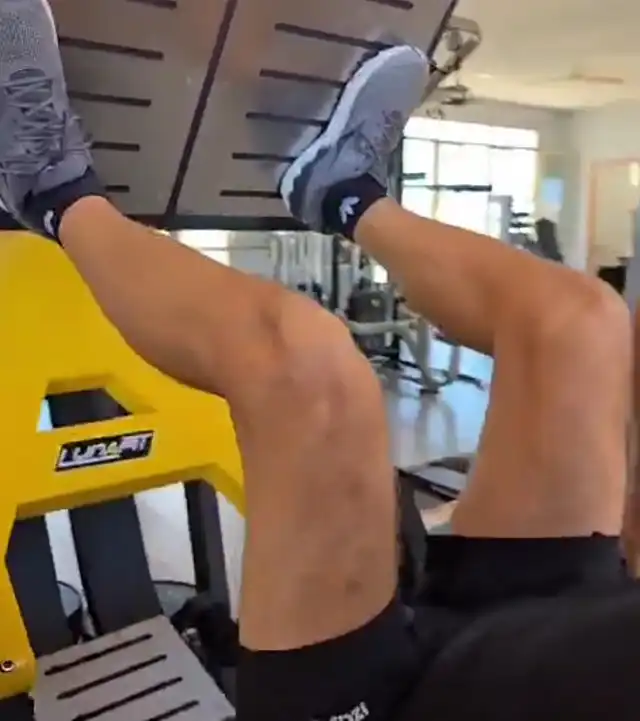 Persona realizando ejercicio de prensa vertical en máquina de gimnasio.